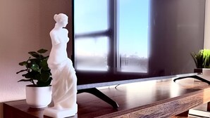 Uma estátua sobre uma mesa de madeira, com uma janela ao fundo.