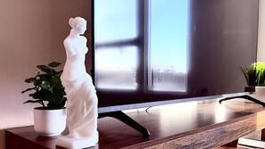Een beeldje op een houten tafel, met een raam op de achtergrond.