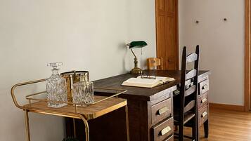 Un coin repas avec une table en bois, des chaises, un chariot doré contenant de la verrerie et un crâne de vache accroché au mur.