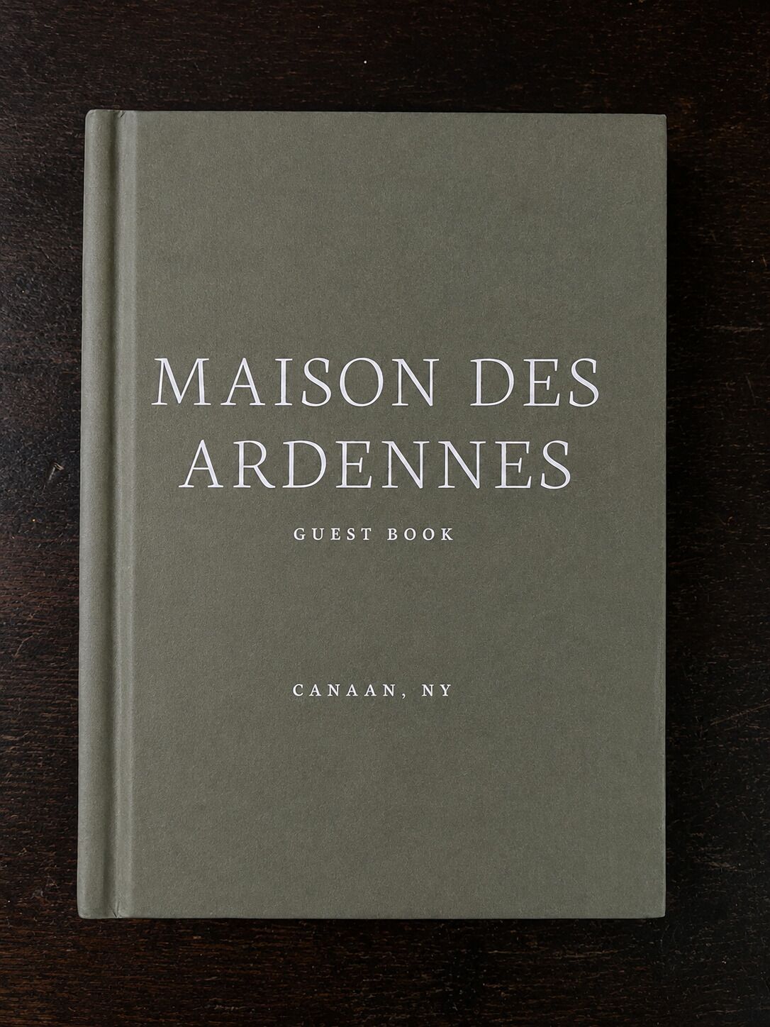 A book titled 'MAISON DES ARDENNES GUEST BOOK' with the location 'CANAAN, NY' on its cover.