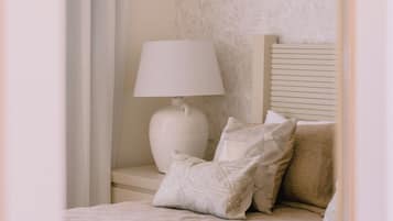 Een slaapkamer met een bed, nachtkastje, lamp en een raam met gordijnen.