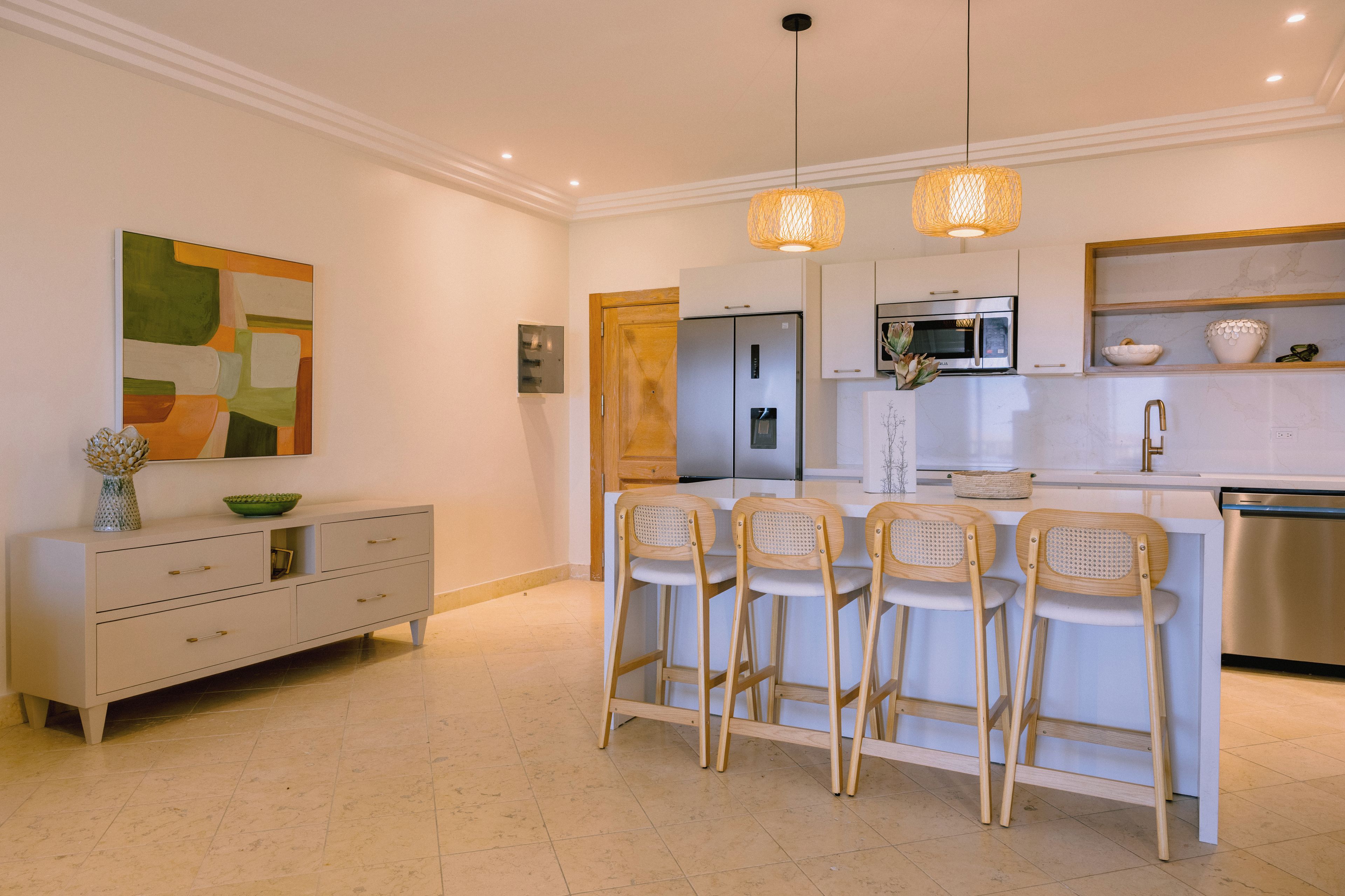A modern kitchen with a central island, bar stools, a refrigerator, an oven, and a microwave.
