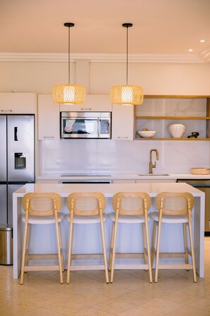 A modern kitchen with a central island, stainless steel appliances, and a microwave above the island. - Marina View 2BR Apartment  Cap Cana (Punta Cana)