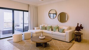 A modern living room with a sectional sofa, a round coffee table, and a ceiling fan. - Marina View 2BR Apartment  Cap Cana (Punta Cana)