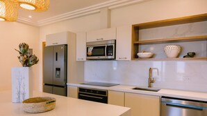 A modern kitchen with stainless steel appliances, a marble countertop, and a built-in oven. - Marina View 2BR Apartment  Cap Cana (Punta Cana)