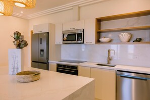 Cozinha moderna com eletrodomésticos de aço inoxidável, bancada de mármore e forno embutido.