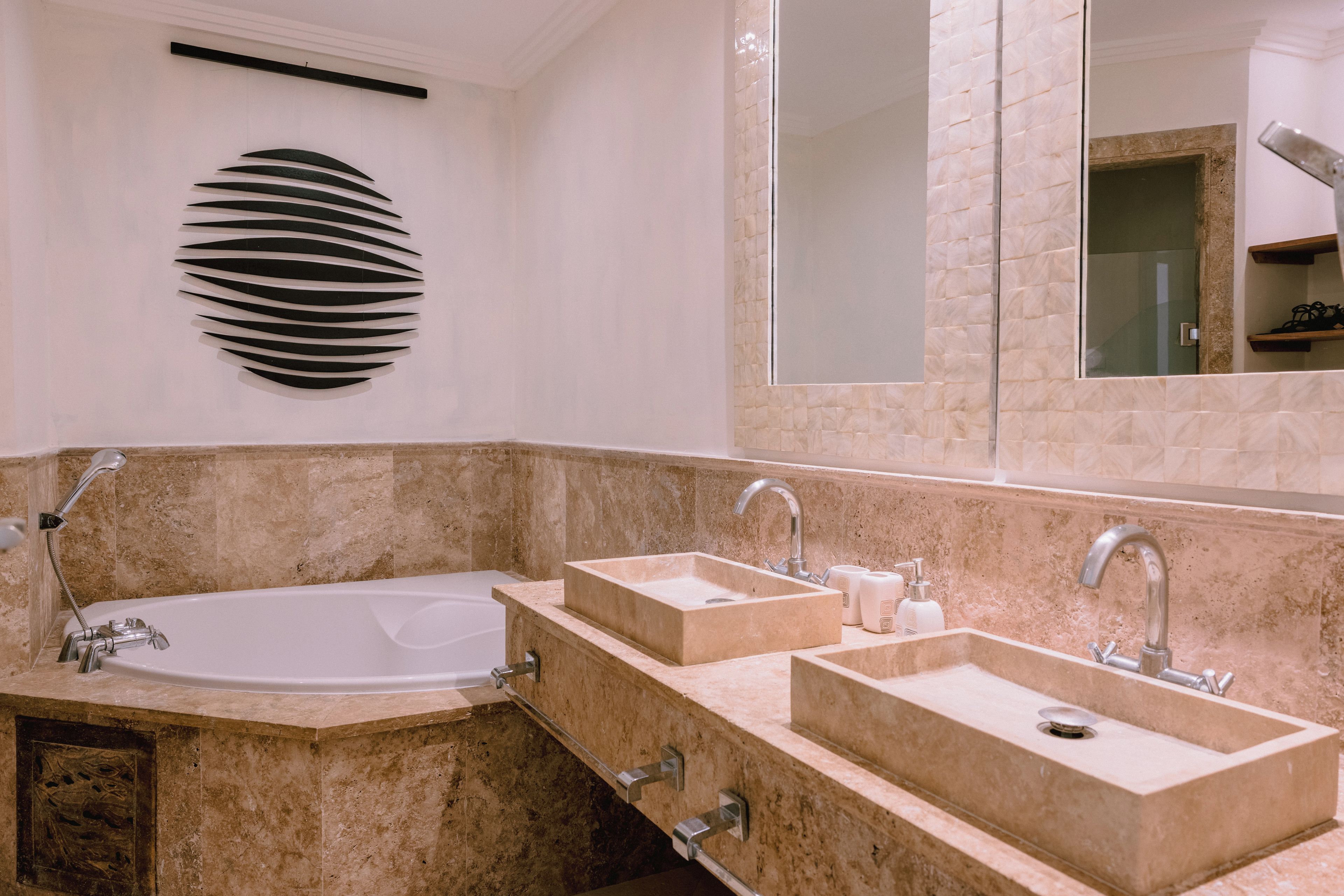 A bathroom with a bathtub, two sinks, and a large mirror.
