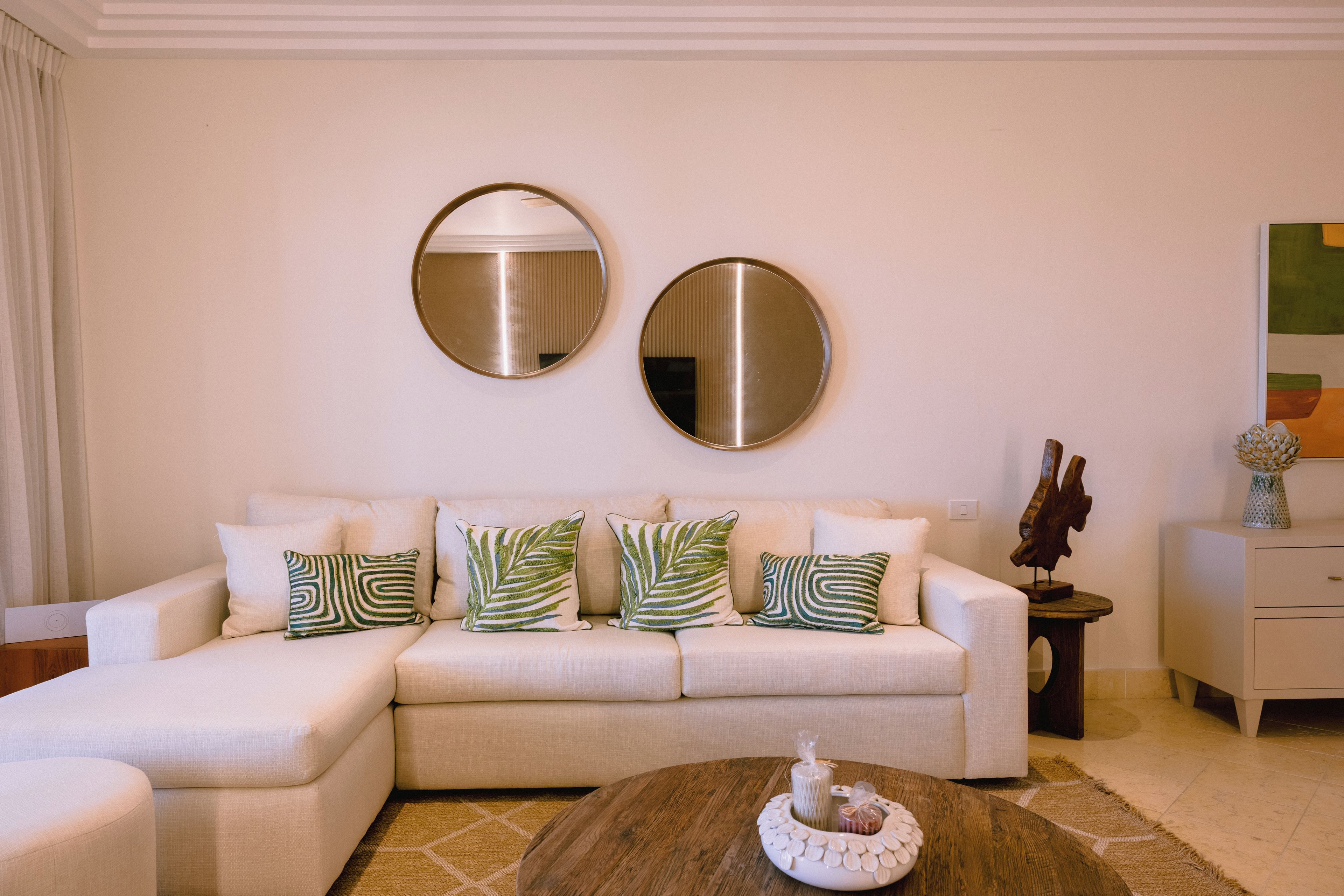 A living room with a sofa, two round mirrors, and decorative pillows.