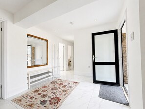 A spacious hallway with a white floor, a patterned rug, a bench, and a large mirror. - Spacious Garden Retreat w/ Free Parking Near Canterbury (Canterbury)