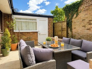 An outdoor patio with wicker furniture, a table with a glass top, and potted plants. - Spacious Garden Retreat w/ Free Parking Near Canterbury (Canterbury)