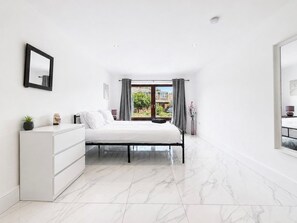 Ein modernes Schlafzimmer mit einem Bett, einer Kommode und Blick ins Freie.
