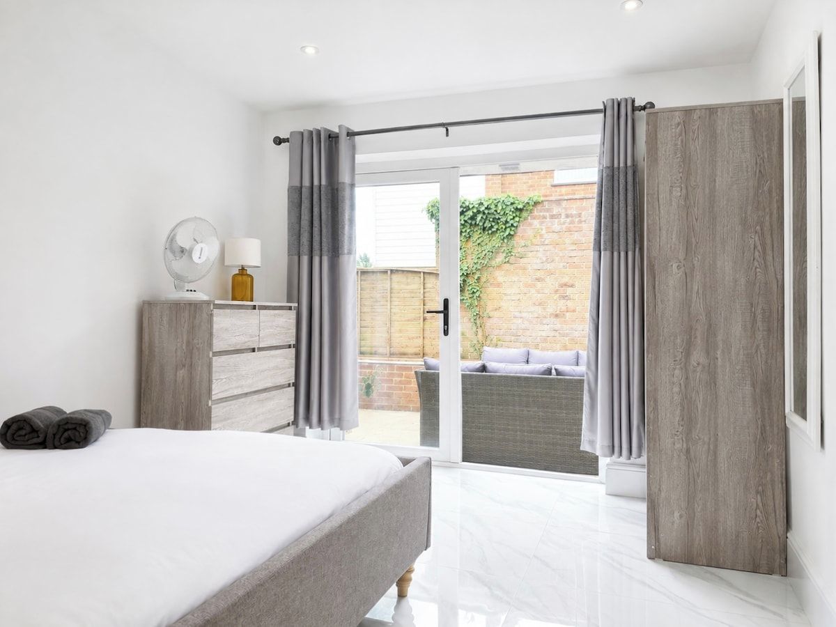 Un dormitorio moderno con cama, cómoda y vista a un patio exterior.