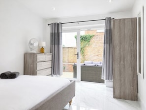 A modern bedroom with a bed, a dresser, and a view of an outdoor patio. - Spacious Garden Retreat w/ Free Parking Near Canterbury (Canterbury)