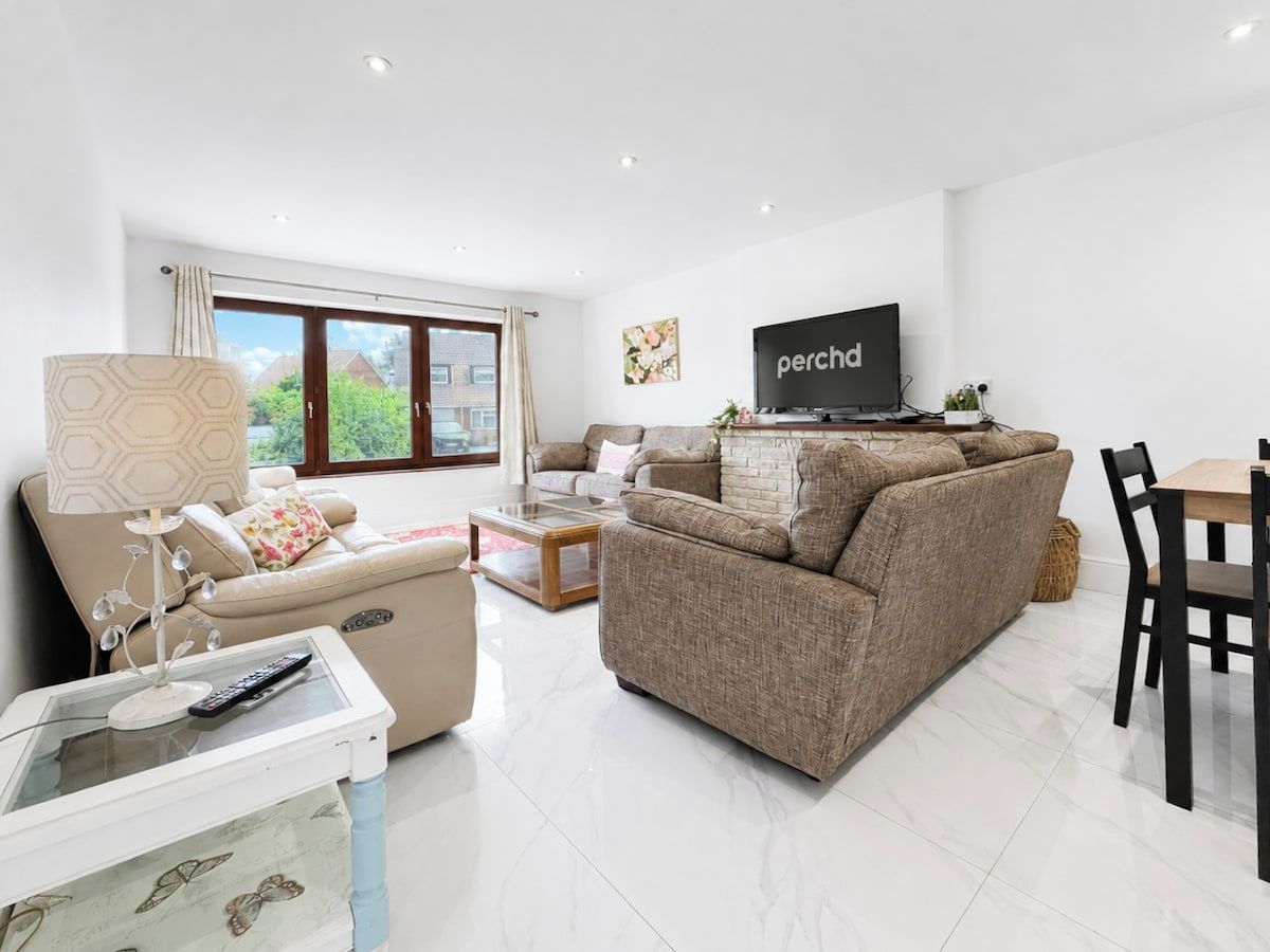 A modern living room with a sofa, a coffee table, a TV, and a dining area.