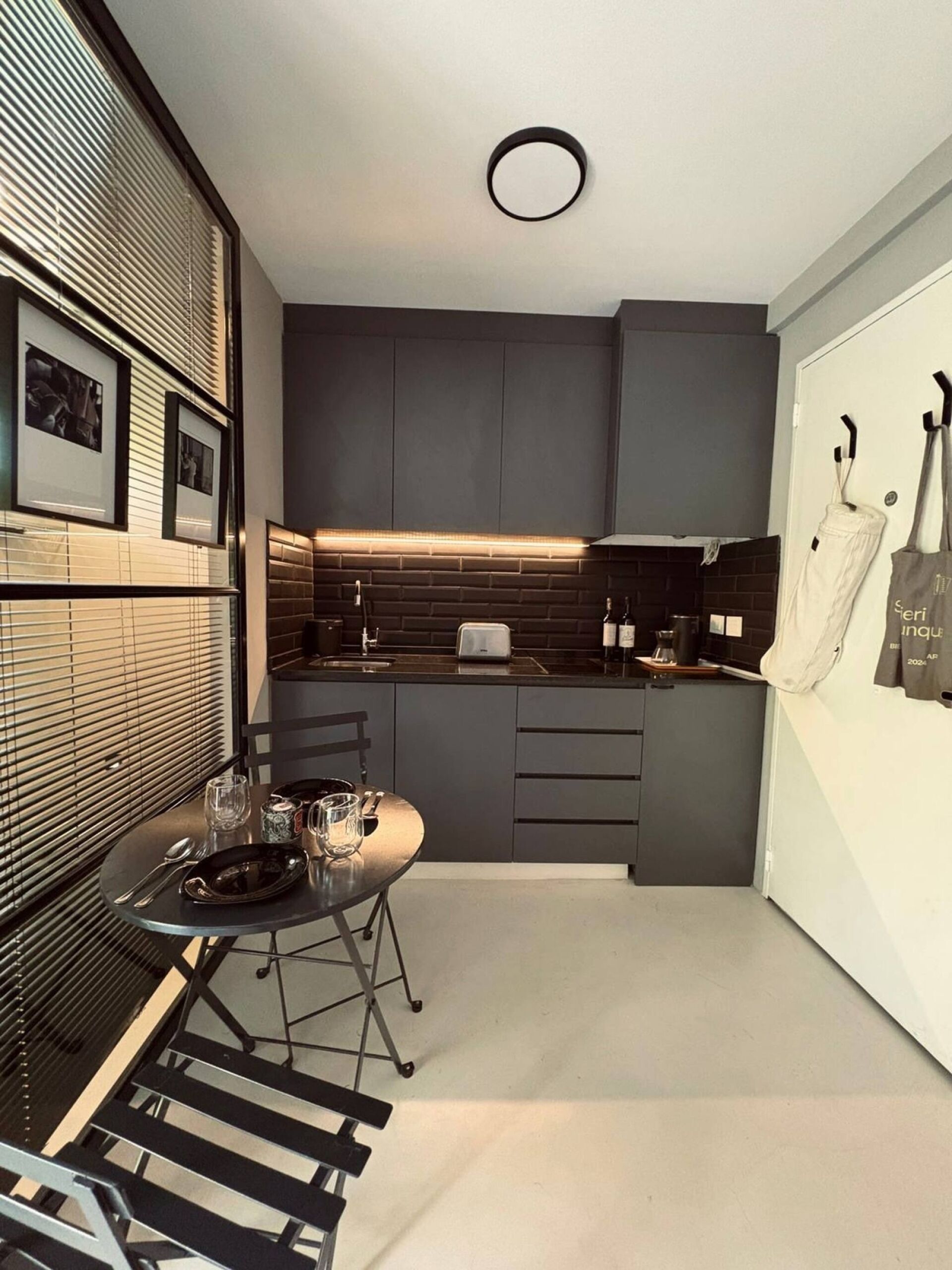 A modern kitchen with a dining area, featuring a round table with chairs, a built-in oven, and a coffee machine.