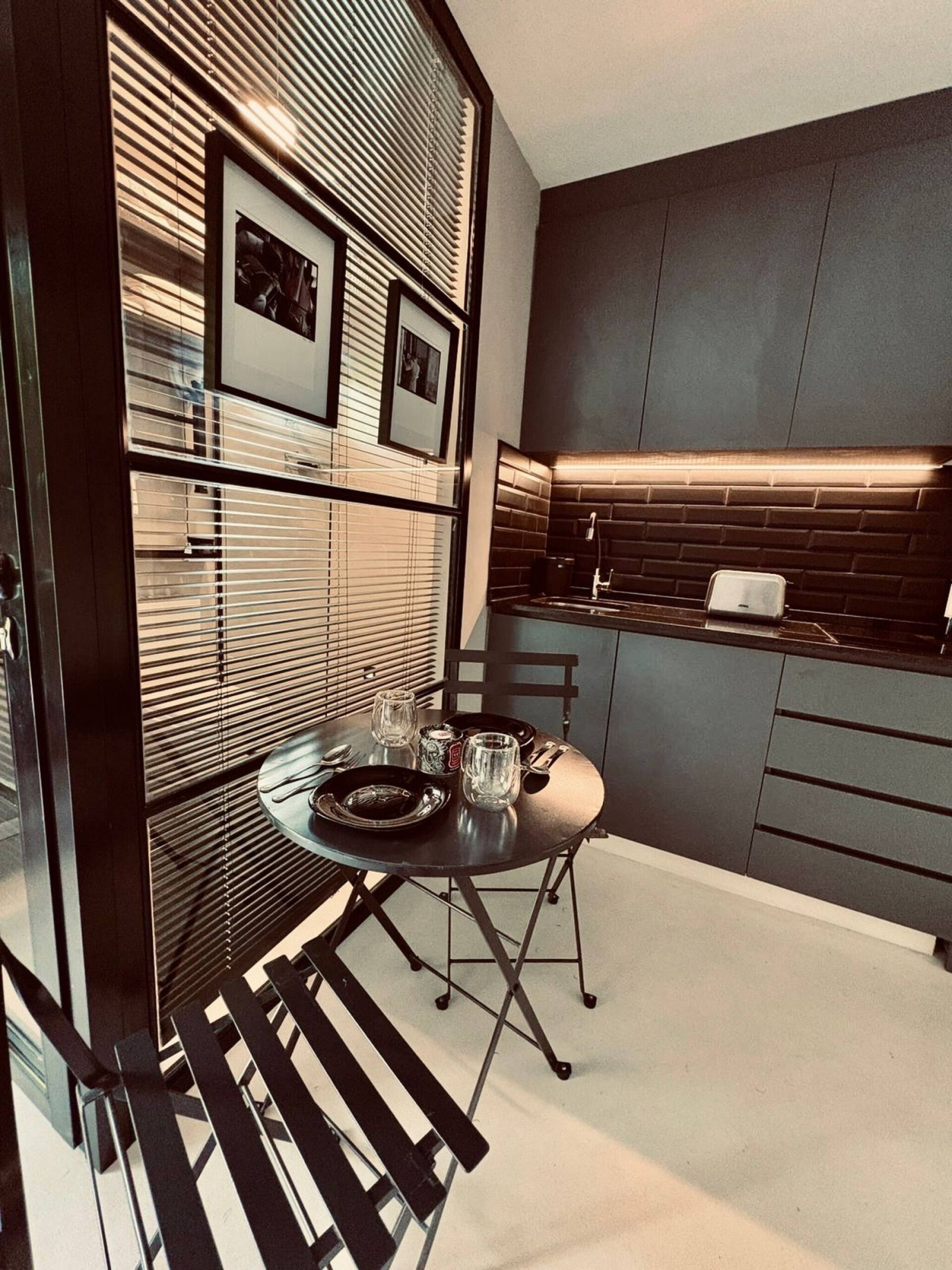 A modern kitchen with a built-in stove, a dining area with a table and chairs, and a wall with framed pictures.