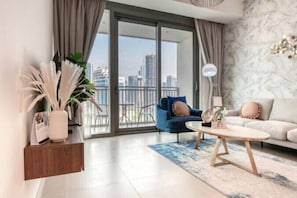 A modern living room with a sofa, a coffee table, and a chair. There is a large window with a view of the city. - 52 42 Tower 1 (Dubai)