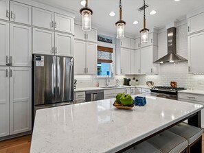 A modern kitchen with white cabinetry, stainless steel appliances, and a marble island. - Sunshine & Tailwinds (Santa Rosa Beach)