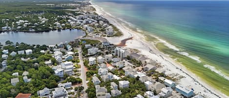 An aerial view of a coastal residential area with houses, a beach, and a body of water.
