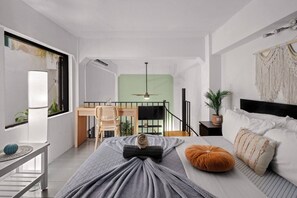 A modern bedroom with a bed, a desk, a chair, a staircase, and a view of the outdoors. - Historic Loft in the Heart of Old San Juan (San Juan)