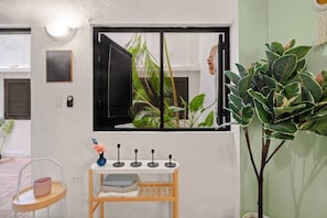 A room with a window, a small table with a vase, and a potted plant. - Historic Loft in the Heart of Old San Juan (San Juan)