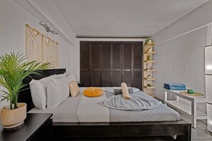 A modern bedroom with a bed, bedside tables, a plant, and a wardrobe. - Historic Loft in the Heart of Old San Juan (San Juan)