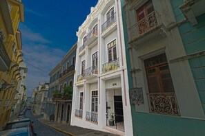 A narrow street lined with multi-story buildings, some with balconies and decorative railings. - Historic Loft in the Heart of Old San Juan (San Juan)