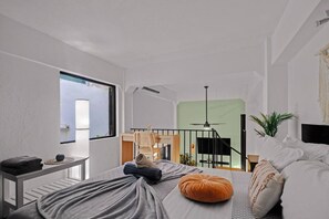 A modern bedroom with a bed, a desk, a chair, and a view of a balcony. - Historic Loft in the Heart of Old San Juan (San Juan)