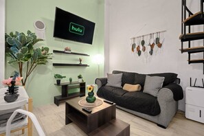 A living room with a sofa, a coffee table, a TV mounted on the wall, and a plant. - Historic Loft in the Heart of Old San Juan (San Juan)
