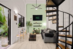 A modern living room with a green accent wall, a black sofa, a coffee table, and a spiral staircase. - Historic Loft in the Heart of Old San Juan (San Juan)