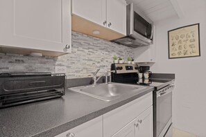 A modern kitchen with white cabinets, a stainless steel sink, a built-in oven, and a microwave. - Historic Loft in the Heart of Old San Juan (San Juan)