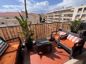 A balcony with outdoor furniture, a potted plant, and a view of surrounding buildings. - Riviera Suite Apartment for 3–4 people, a 12-minute walk from the Cannes Train Station (Cannes)