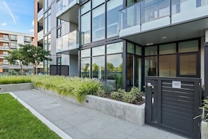A modern building with large windows, a private patio, and a well-maintained garden area. - Beachside Stay in Kelowna | Pool, Gym & Sauna (Kelowna)