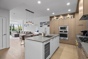A modern kitchen with a central island, stainless steel appliances, and a dining area with a sofa and chairs.
