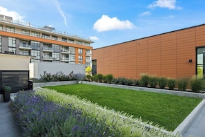 A modern building with a flat roof, a courtyard with a well-maintained lawn, and a variety of plants.