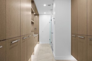 A narrow hallway with wooden cabinets and a glass shower enclosure.