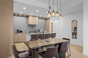 A modern kitchen with a central island, built-in cabinets, and a dining area with a wooden table and leather chairs.