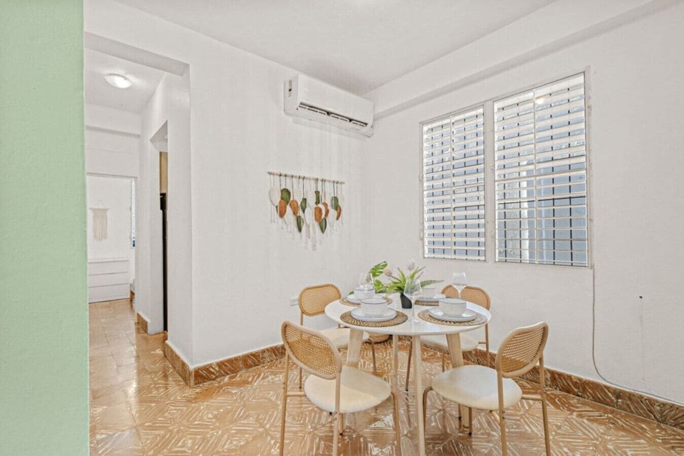 A dining area with a round table, four chairs, and a window with blinds.