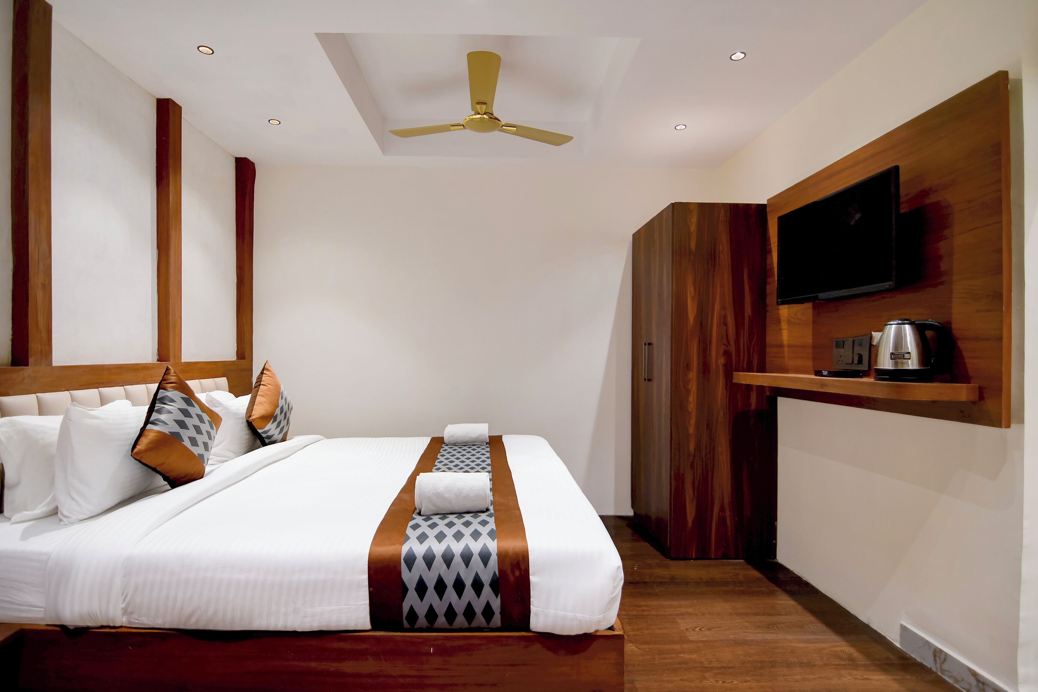 Ein Hotelzimmer mit einem Bett, einem Fernseher, einer Kaffeemaschine und einem Deckenventilator.