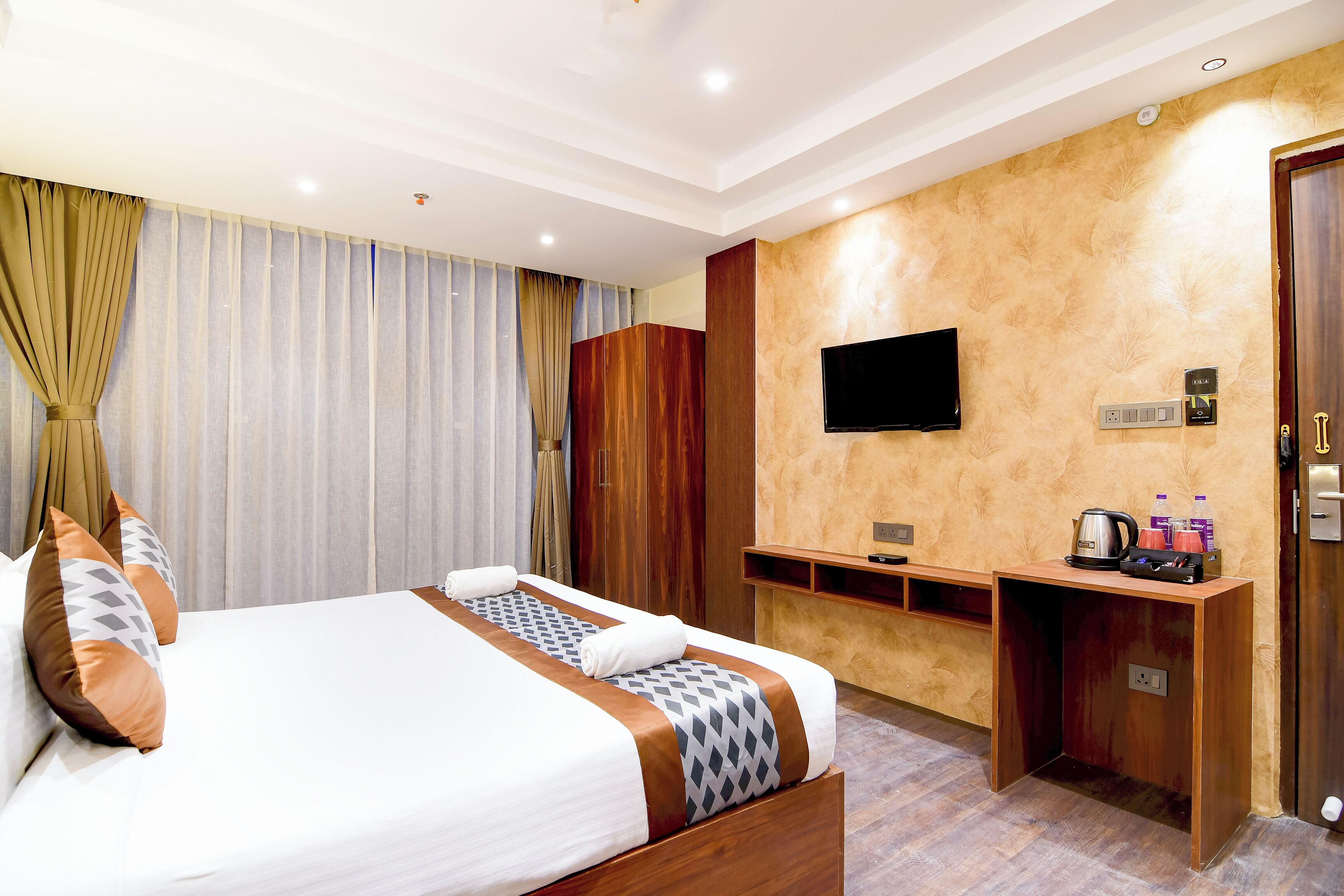 A hotel room with a bed, a desk, a flat-screen TV, and a coffee machine.