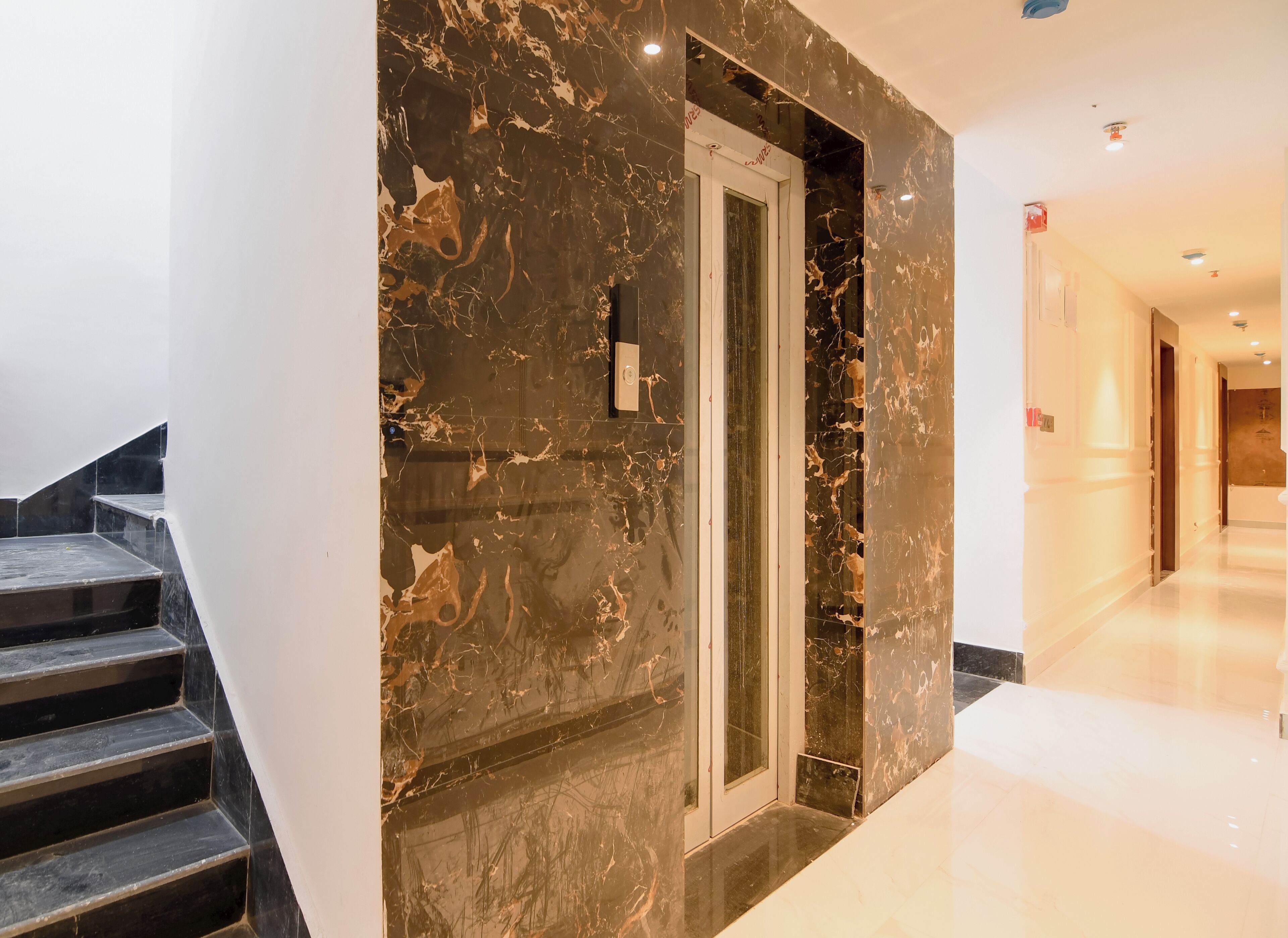 Ein modernes Interieur mit Marmorwand, Glastür und Treppe.