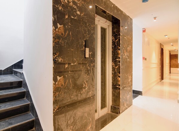 A modern interior with a marble wall, a glass door, and a staircase.