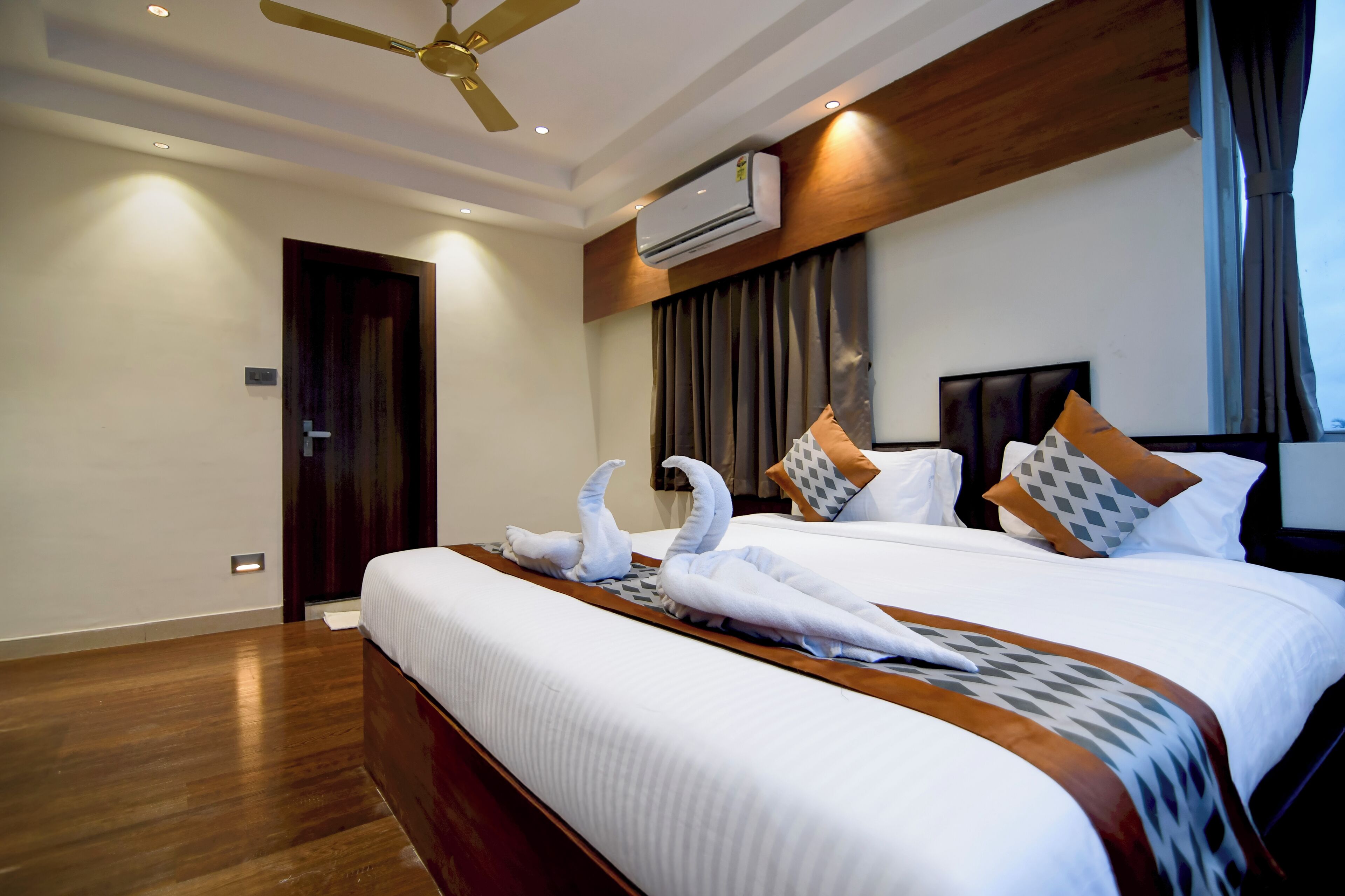 A hotel room with a large bed, wooden headboard, and a ceiling fan.
