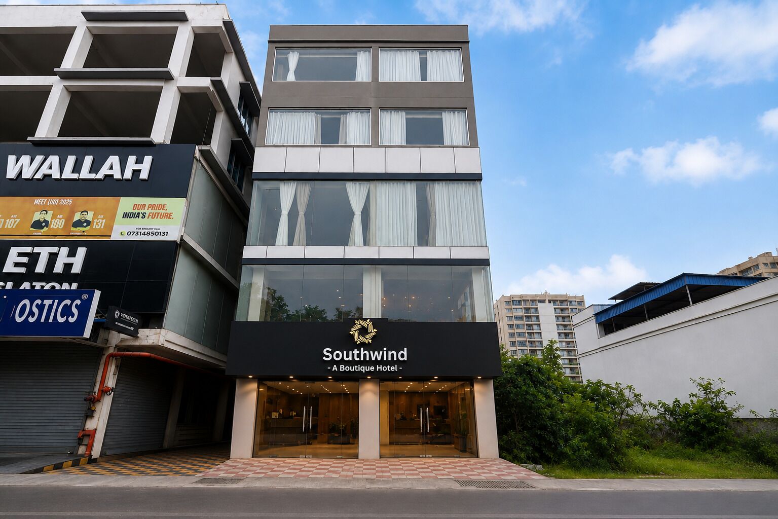 Un hotel moderno con un letrero llamativo que dice 'Southwind Boutique Hotel' y edificios comerciales aledaños.