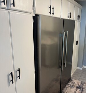 A kitchen with white cabinets and a stainless steel refrigerator.