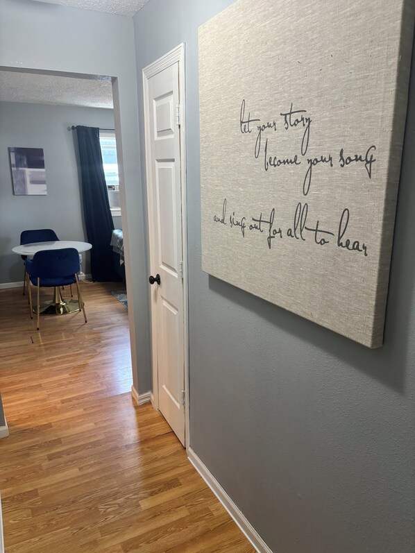 A room with a wooden floor, a white door, and a wall with a motivational quote.