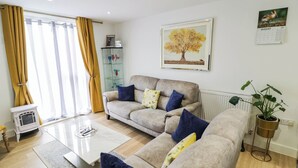 A living room with a sofa set, a coffee table, a radiator, and a potted plant. - 4 Goldcrest Close (Daventry)