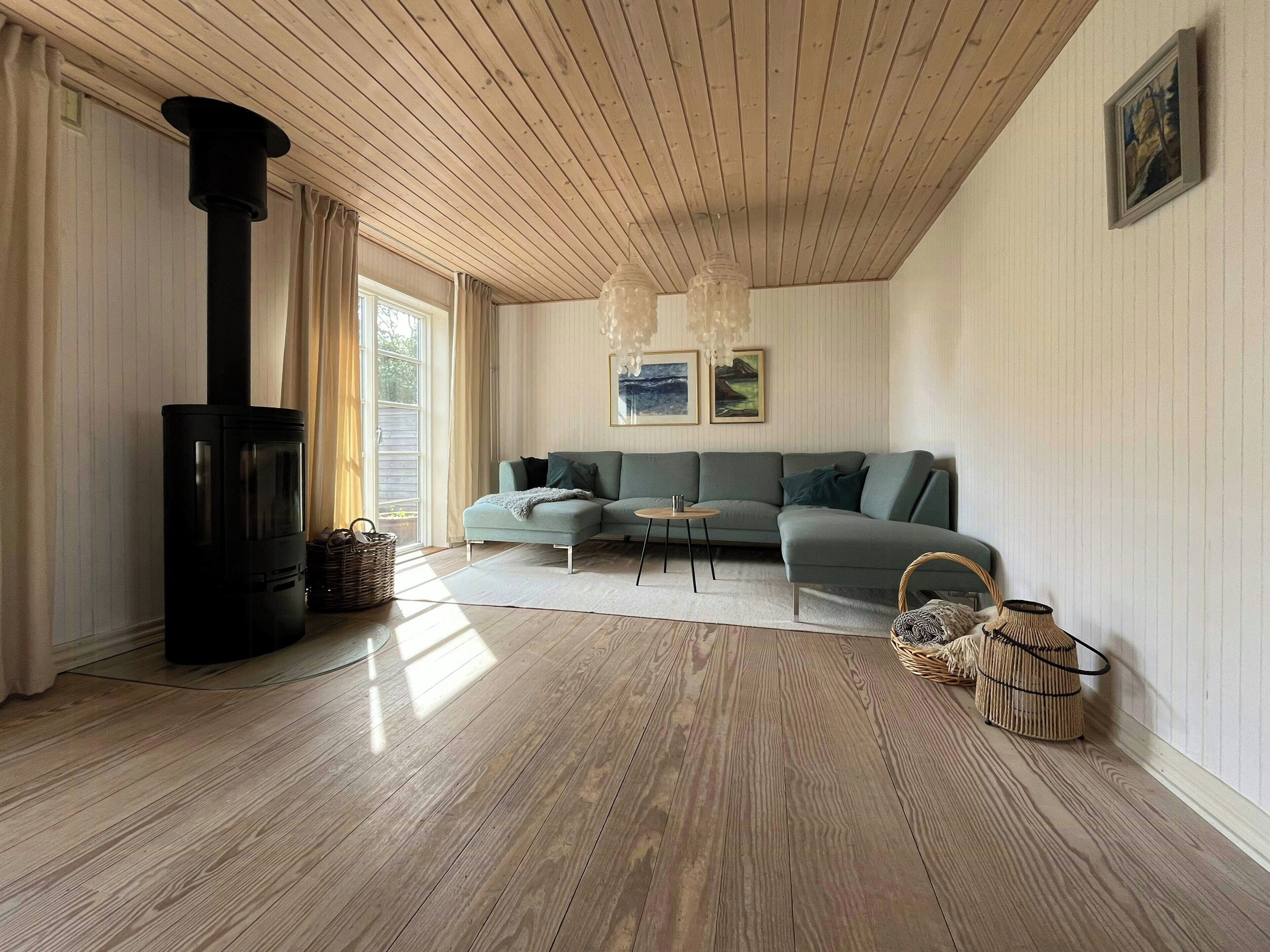 A modern living room with a sectional sofa, a black wood-burning stove, and a large window with curtains.
