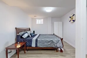 Et soveværelse med seng, sengebord, lampe og en redningskrans på væggen.