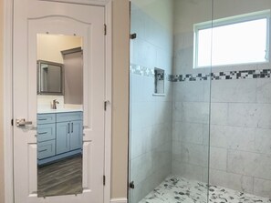 Een badkamer met een douche, een wastafel en een spiegel.
